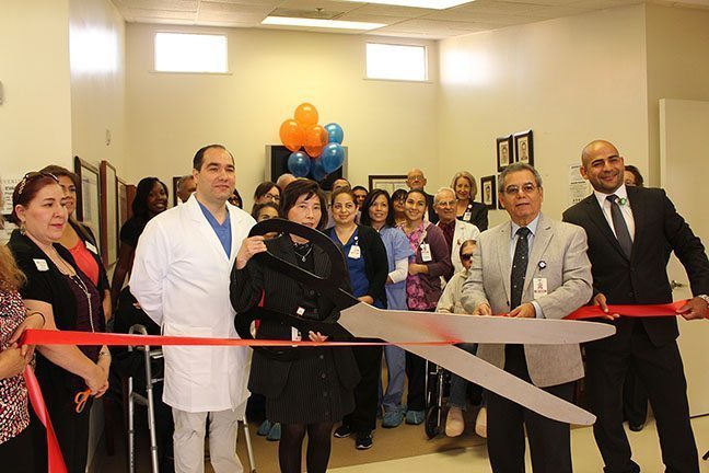 Group photo of hospital staff and community members at Beverly Hospital's Wound Care Center Ribbon cutting ceremony. President & CEO Alice Cheng holds large scissors about to cut the ribbon.