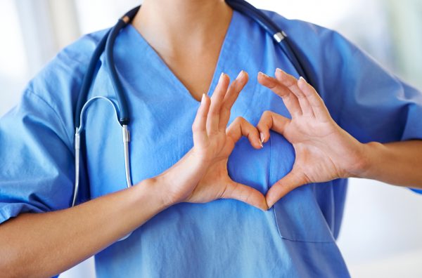 Cropped image of a nurse making a heart shape on her chest with her hands