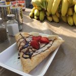 A crepe with chocolate drizzle, strawberries, and banana on top