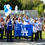 A close up front view of Beverly Hospital employees with Dodgers jerseys or flags waving to the passing cars.