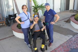 Senen Robles (an older patient who is wheelchair bound) smiles at the camera with Dr. Ara Kelekian on left side and a wound care center nurse on his right side