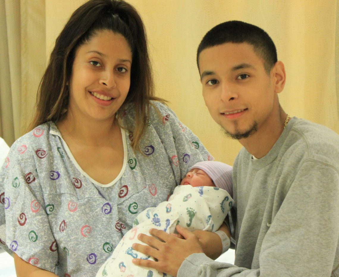 Parents of 2019 Beverly Hospital's New Year baby, Estela, hold her and smile at the camera.