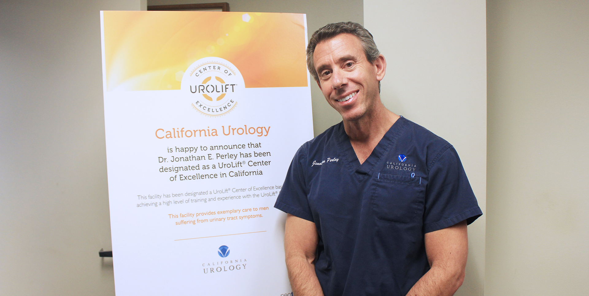 Male (Dr. Jonathan Perley) standing next to sign stating he received UroLift® Center of Excellence Recognition.