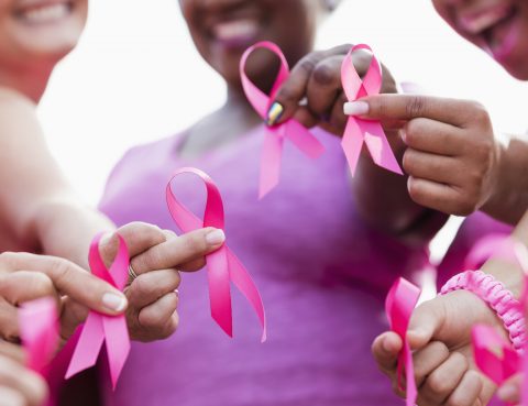 Close up of group of women holding pink breast cancer awareness ribbons
