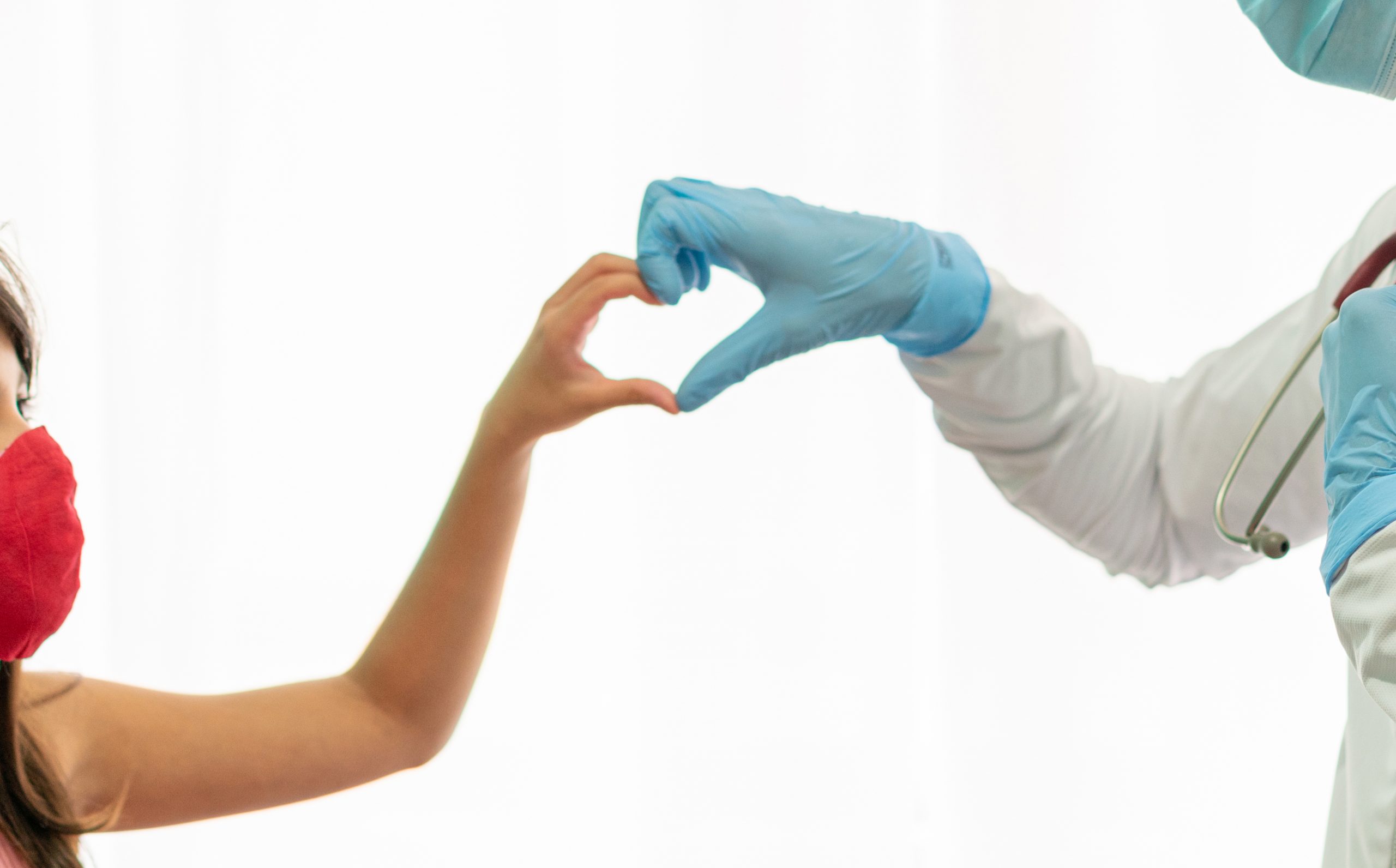 Close up shot of physician and child making a heart with their hands