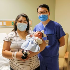 Pomona Ramos holds her baby and stands next to her OBGYN, Yu Chen, in hospital room